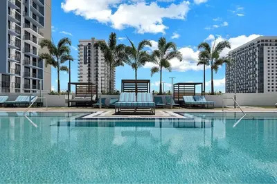 a swimming pool with lounge chairs and palm trees at Stylish Studio with Pool View at the Heart of Downtown Doral in Miami