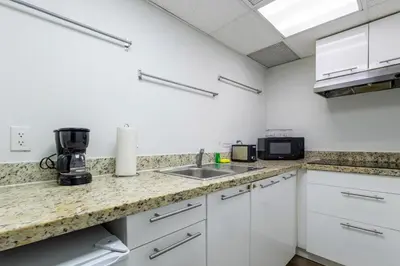 a kitchen with white cabinets and a counter top at Coastal 2BR Escape | Walk to Beach & 2 Queen Beds in Miami Beach
