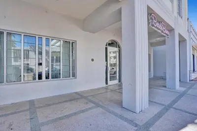 a white building with a door and windows at Coastal 2BR Escape | Walk to Beach & 2 Queen Beds in Miami Beach