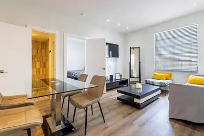 a dining room and living room with a glass table at Coastal 2BR Escape | Walk to Beach & 2 Queen Beds in Miami Beach