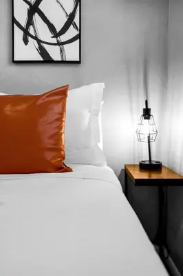 a bed with an orange pillow and a lamp on a table at Cozy 1BR Retreat | 6-Min to Beach + Free Parking in Dania Beach