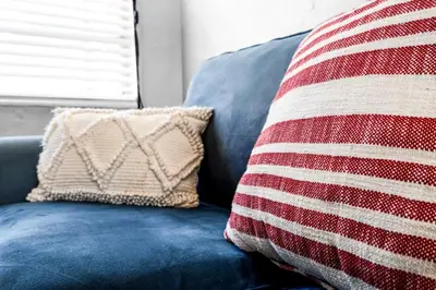 a blue couch with a red and white striped pillow at Cozy 1BR Retreat | 6-Min to Beach + Free Parking in Dania Beach