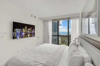 a white bedroom with a bed and a large window at W South Beach 1B Residence Ocean View in Miami Beach