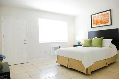 a white bedroom with a large bed with green pillows at Mimo 10 - Kitchen - Walkable - Fast WiFi - Free Parking in Miami