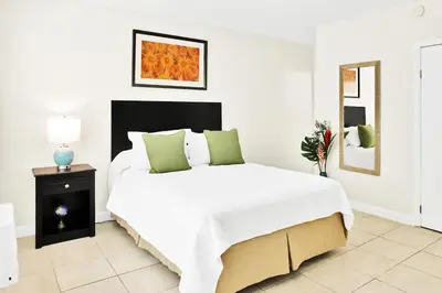 a white bedroom with a large white bed with green pillows at Mimo 10 - Kitchen - Walkable - Fast WiFi - Free Parking in Miami