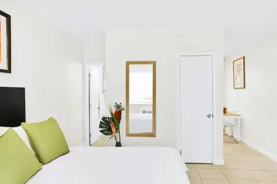 a white bedroom with a bed and a mirror at Mimo 10 - Kitchen - Walkable - Fast WiFi - Free Parking in Miami