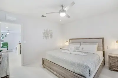 a white bedroom with a bed and a ceiling fan at Beachside Bliss, 1BR Condo with Pool at Dania Beach in Dania Beach