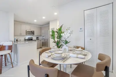 a kitchen and dining room with a table and chairs at Beachside Bliss, 1BR Condo with Pool at Dania Beach in Dania Beach