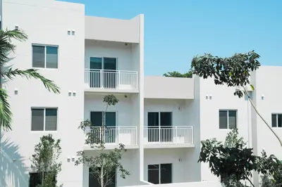 an apartment building with balconies and trees at Beachside Bliss, 1BR Condo with Pool at Dania Beach in Dania Beach