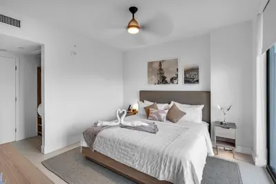a bedroom with a large bed with white walls at Sunlit 1BR Condo In Downtown Miami in Miami