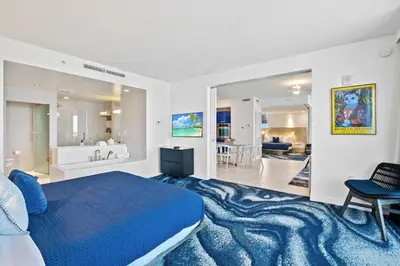 a bedroom with a blue bed and a bathroom at 23rd Floor W 2BR with Den, Ocean Views, Sleeps 8 in Fort Lauderdale