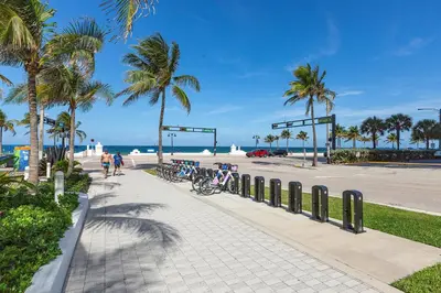 a sidewalk next to a beach with palm trees at 23rd Floor W 2BR with Den, Ocean Views, Sleeps 8 in Fort Lauderdale