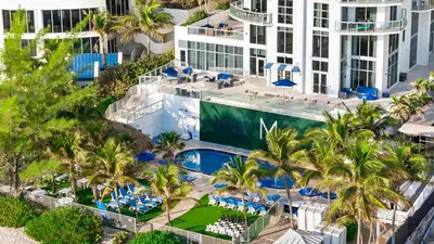 an aerial view of a resort with a pool and palm trees at Luxury Top-Level Oasis - Oceanfront Views & Resort Perks in Sunny Isles Beach