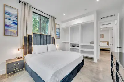 a bedroom with a white bed and a large window at Wonderful New Tropical Pool House North Miami in Gold Coast Heliport