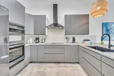 a kitchen with white cabinets and stainless steel appliances at Stunning Tropical Pool House North Miami in Gold Coast Heliport