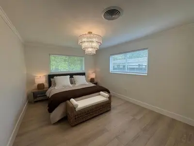 a bedroom with a large bed and a chandelier at Chic-ness Oasis NOW HEATED POOL ! in Cutler Bay