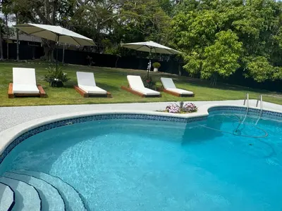 a swimming pool with chairs and umbrellas in a yard at Chic-ness Oasis NOW HEATED POOL ! in Cutler Bay