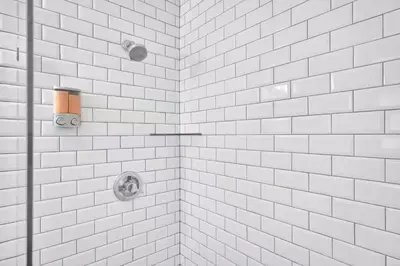 a white tiled shower with white subway tiles at 175 Casa Buena Blanca in Miami