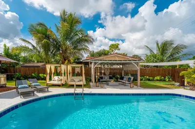 a swimming pool with chairs and a gazebo at Top Villa Near Beach with Game Room, Hot Tub and Pool in Pembroke Pines