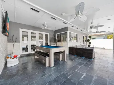 a pool table in a living room with a ceiling fan at The Chill Sunny Casa Near Beaches in Miami Lakes