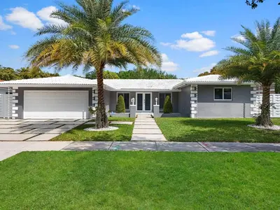 a house with palm trees in front of it at The Chill Sunny Casa Near Beaches in Miami Lakes