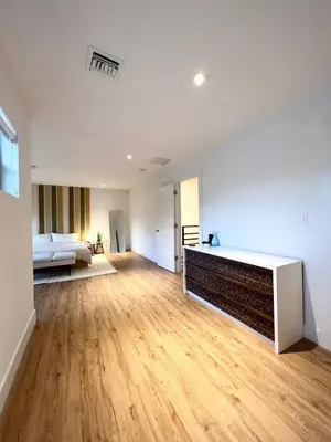 an empty living room with a bed and wooden floors at Lux Retreat with Pool Near Beach in Fort Lauderdale