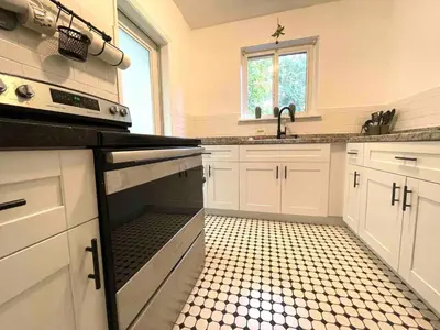 a kitchen with white cabinets and a black oven at 3 Bedroom Apartment with Backyard Oasis in Miami