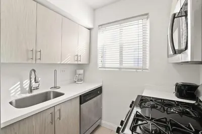a white kitchen with a sink and a stove at Modern Miami Beach Apt King & Sofa Bed Comfort in Miami Beach