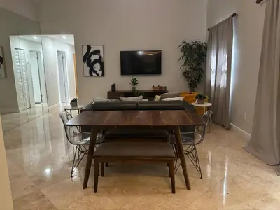 a living room with a wooden table and chairs at Palace at the Gables in Miami