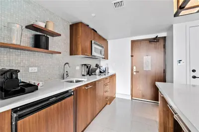 a kitchen with wooden cabinets and a sink at Carillon Miami Beach Private Luxury Suites in Miami Beach