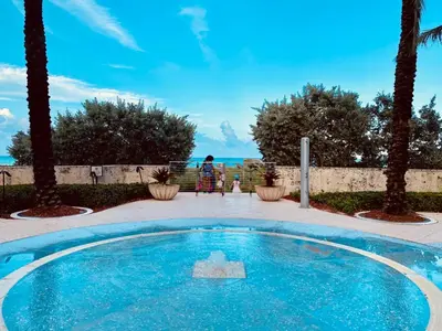 a swimming pool with a person sitting in a chair next to the ocean at Carillon Miami Beach Private Luxury Suites in Miami Beach