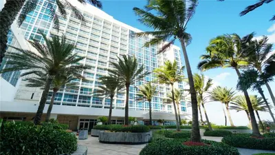 a large building with palm trees in front of it at Carillon Miami Beach Private Luxury Suites in Miami Beach