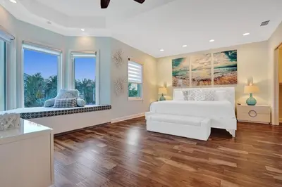 a large bedroom with a white bed and two windows at Massive waterfront home with pool in North Miami Beach