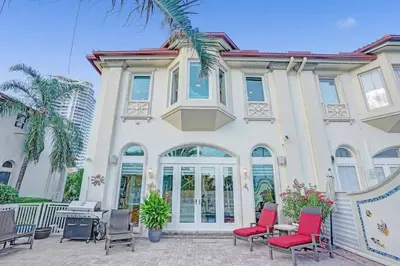 a large white house with red chairs in front of it at Massive waterfront home with pool in North Miami Beach