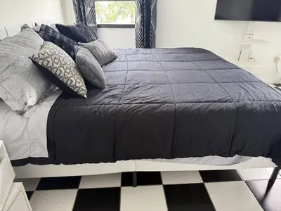 a bed with a black comforter and pillows on it at Walk to South Beach in Miami Beach