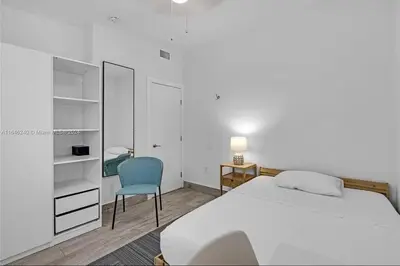 a bedroom with a white bed and a blue chair at Avocado House A Coconut Grove Bungalow in Miami