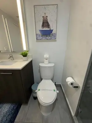 a bathroom with a toilet and a picture of a dog in a tub at Luxury Downtown Miami Stay in Upscale Building in Miami