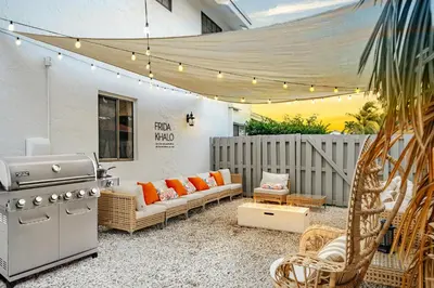 a patio with a grill and a couch and chairs at Waterfront Villa with Beach, Game Room, Cinema and Spa in Pembroke Pines