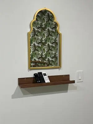 a mirror on a wall with two remotes on a shelf at Tropical Oasis in Pembroke Pines