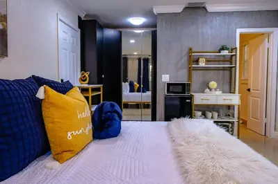 a bedroom with a bed with blue and yellow pillows at Stylish Bedroom Suite in Pembroke Pines