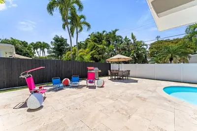 a patio with chairs and a table next to a swimming pool at Family Splash Escape in Fort Lauderdale