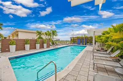a swimming pool at a resort with chairs and trees at Midblock Midtown Miami High Floor 1B Suite W Spa Pool Gym in Miami