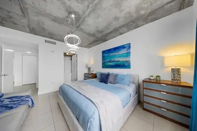 a bedroom with a large bed with a blue blanket at Midblock Midtown Miami High Floor 1B Suite W Spa Pool Gym in Miami