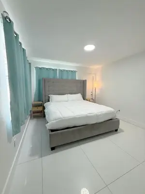a bedroom with a large bed with blue curtains at SeaStays- South Beach Apartments in Miami Beach