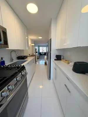 a kitchen with white cabinets and a sink and a stove at SeaStays- South Beach Apartments in Miami Beach
