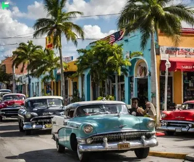 a group of old cars driving down a city street at The Art House Little Havana in Miami