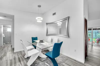 a dining room with a glass table and blue chairs at Lime Haus lime - Your Family Stay in Miami Awaits in Tamiami