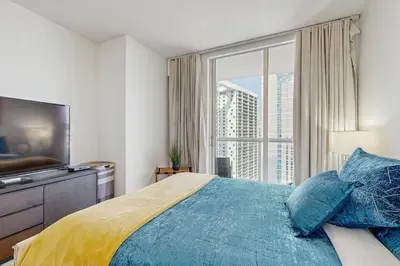 a bedroom with a large window and a bed with blue pillows at Tony Ultimate Experience Miami in Miami