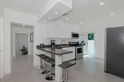 a white kitchen with a counter and stools in it at Stylish Apartment at Brickell ,Free Parking in Miami