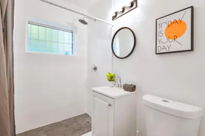 a white bathroom with a toilet and a mirror at Charming Miami Studio in Prime Location in Miami